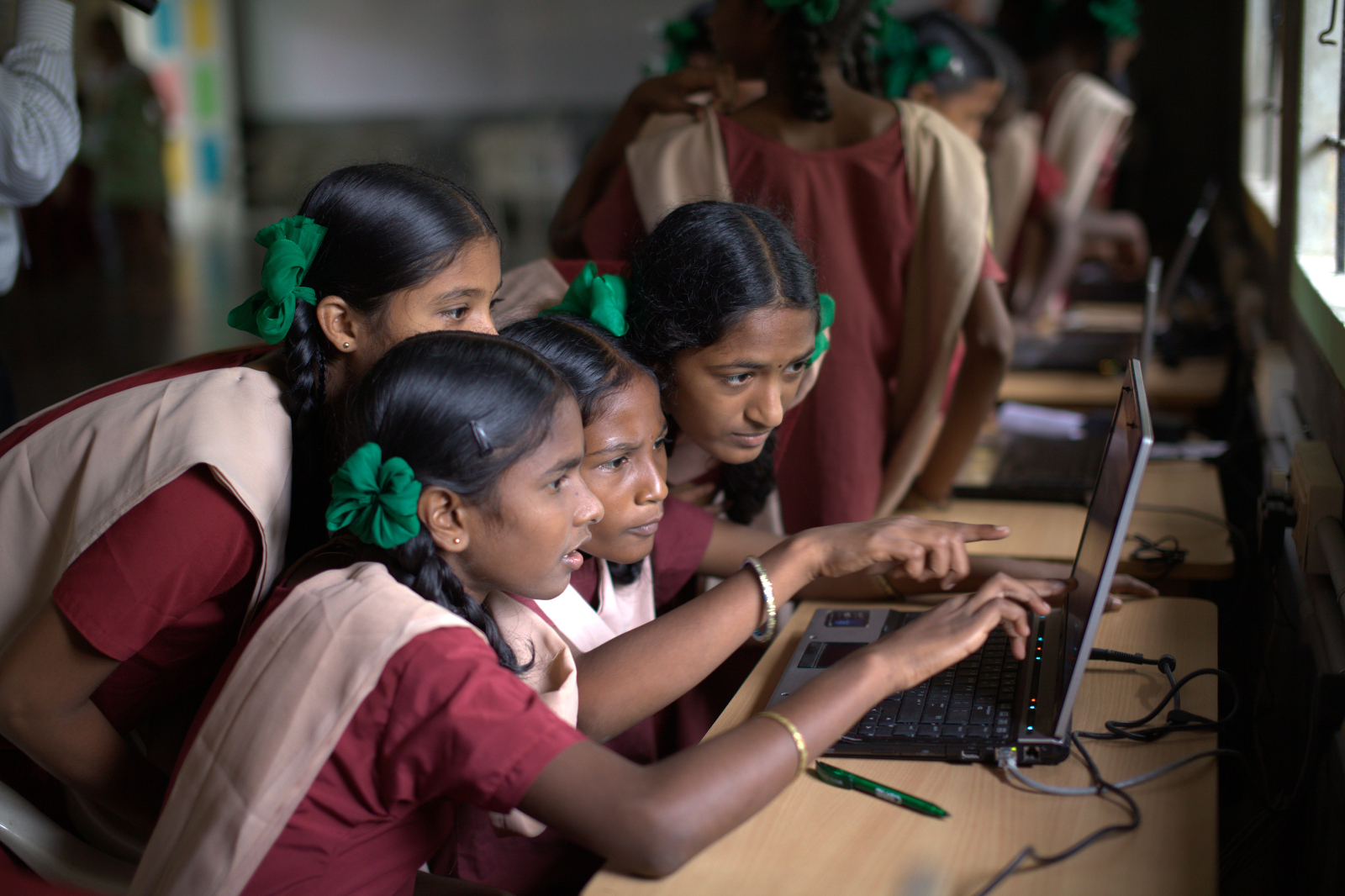Indian school girls in uniforms learning on laptops in Microsoft tech hub classroom