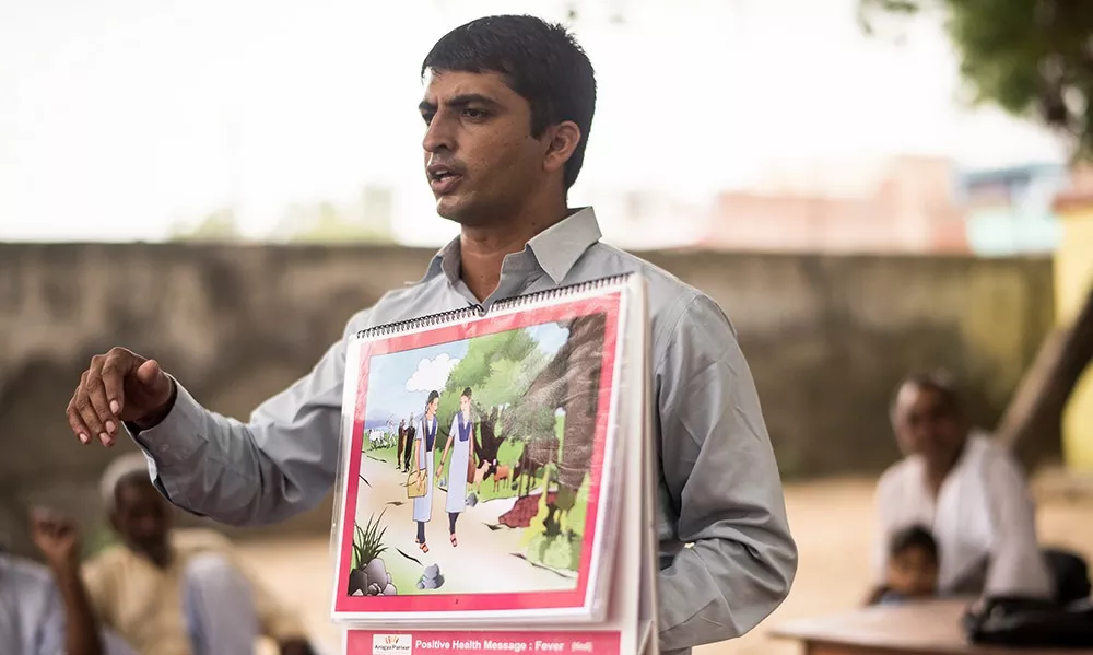 Health educator in India presenting educational poster about preventable diseases and health awareness