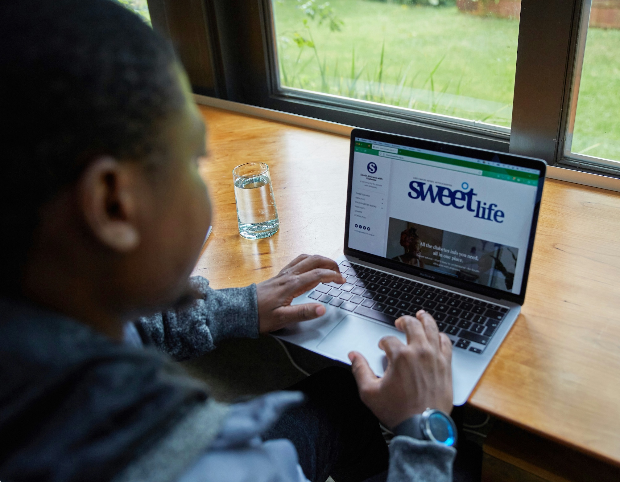 Person working on laptop showing Sweet Life website, representing digital engagement and social impact